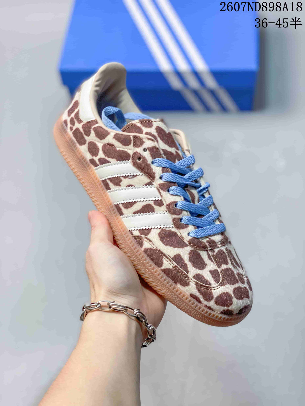 Close side view of a brown-and-cream animal-print Adidas Samba OG sneaker with blue laces and white three-stripe detailing.