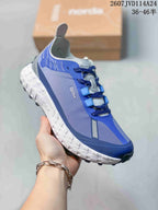 Angled side view of the blue and gray NORDA sneaker showing the mesh-like side panel, lace system, and lugged outsole.