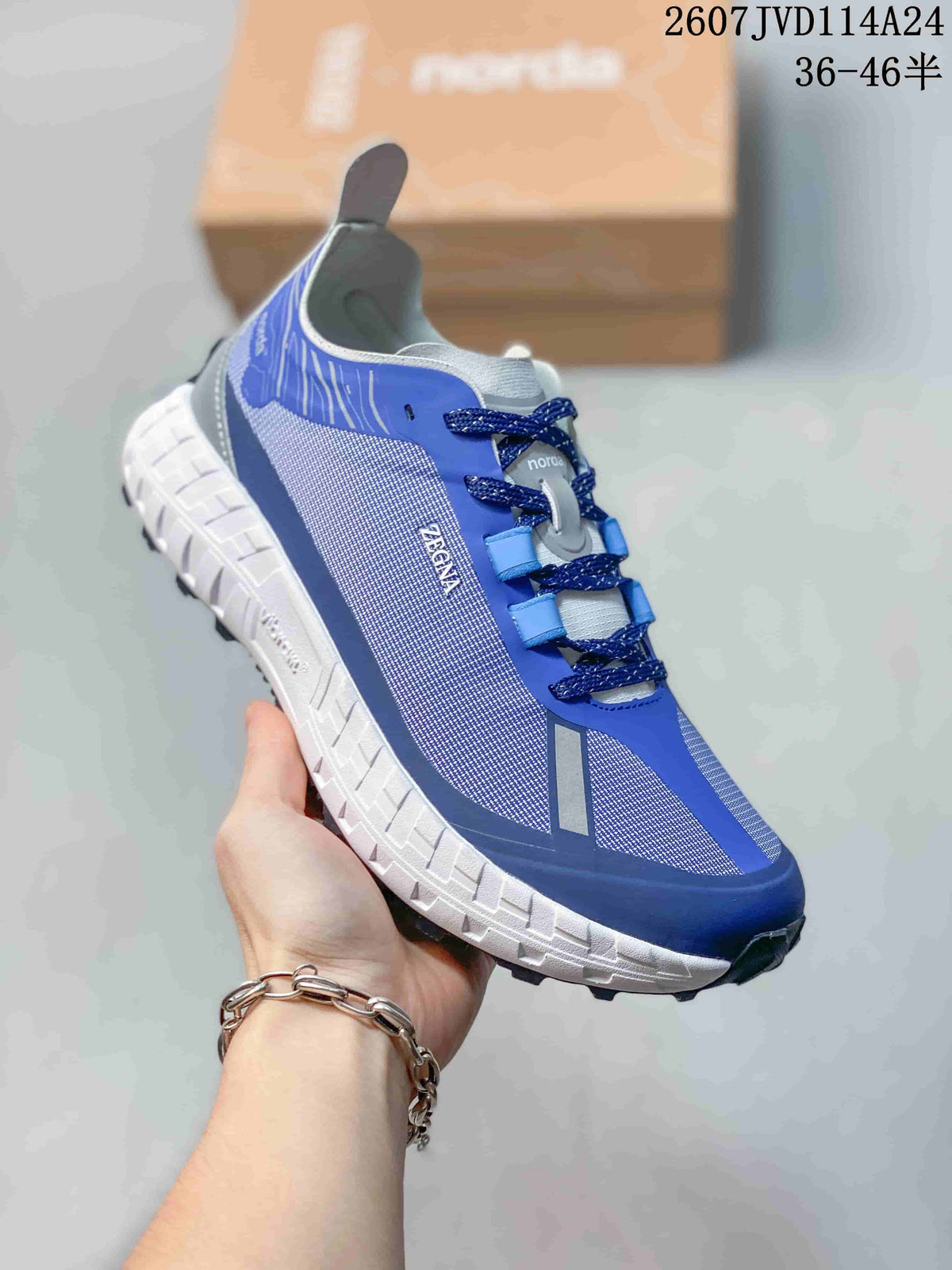 Angled side view of the blue and gray NORDA sneaker showing the mesh-like side panel, lace system, and lugged outsole.