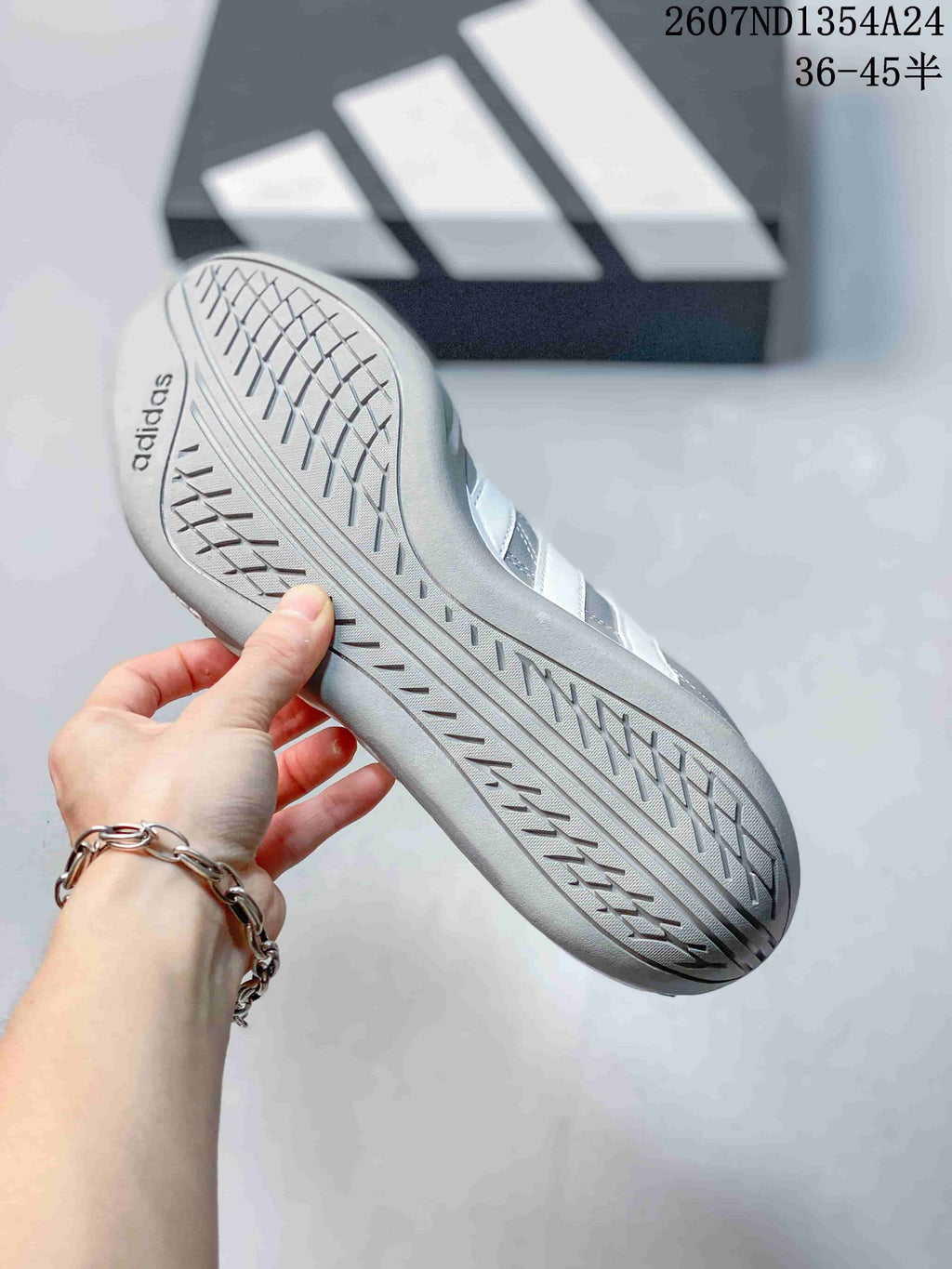 Close view of the patterned outsole and adidas branding on a gray sneaker.