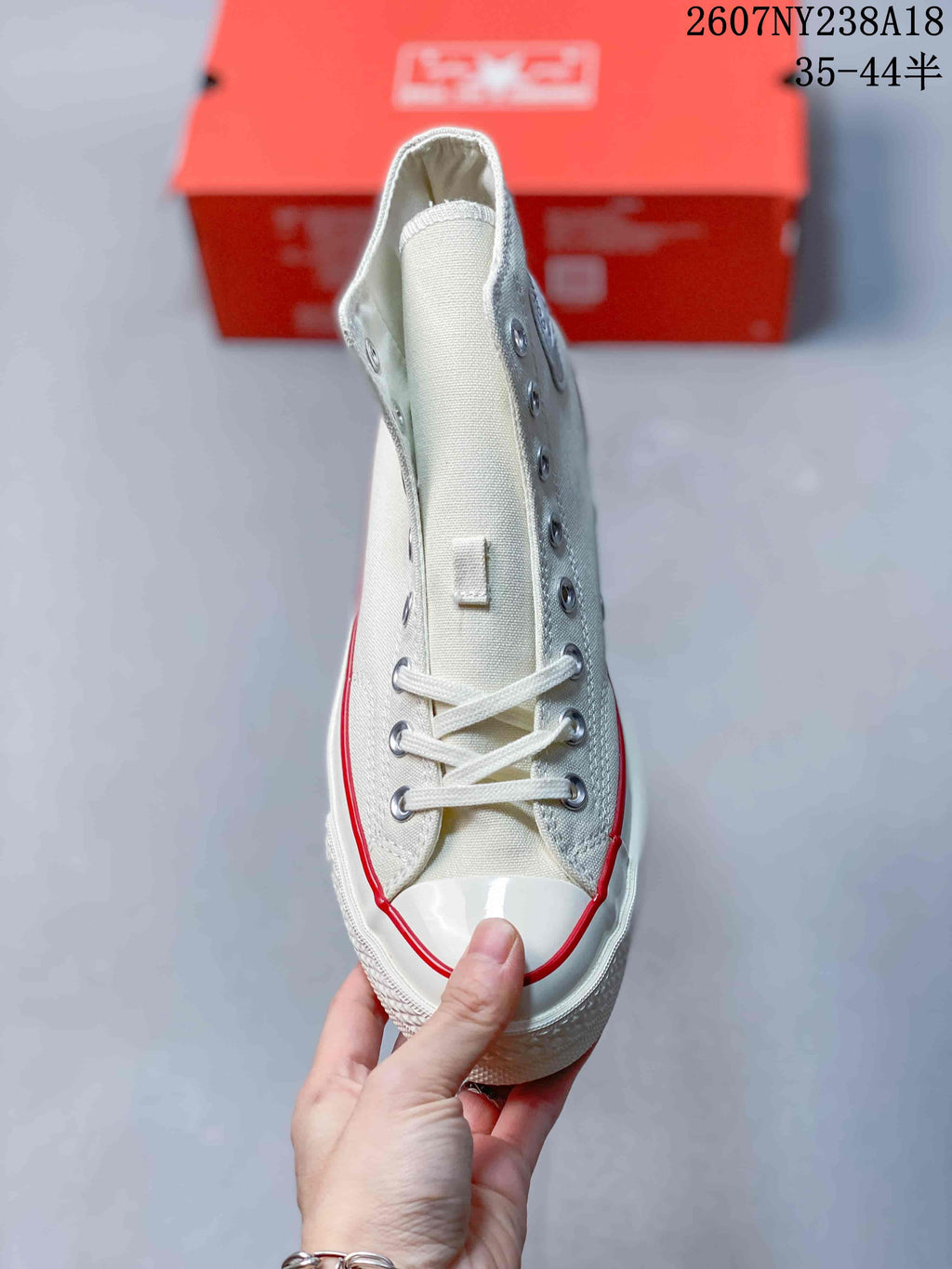 Top view of an off-white high-top sneaker showing the laces, metal eyelets, rubber toe cap, and red foxing stripe.