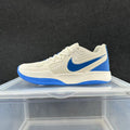 Side view of a cream-colored Nike low-top sneaker with a blue Swoosh and blue outsole accents.