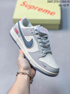 Close view of a gray and white low-top sneaker showing the perforated toe box, padded collar, patterned laces, and side Swoosh.