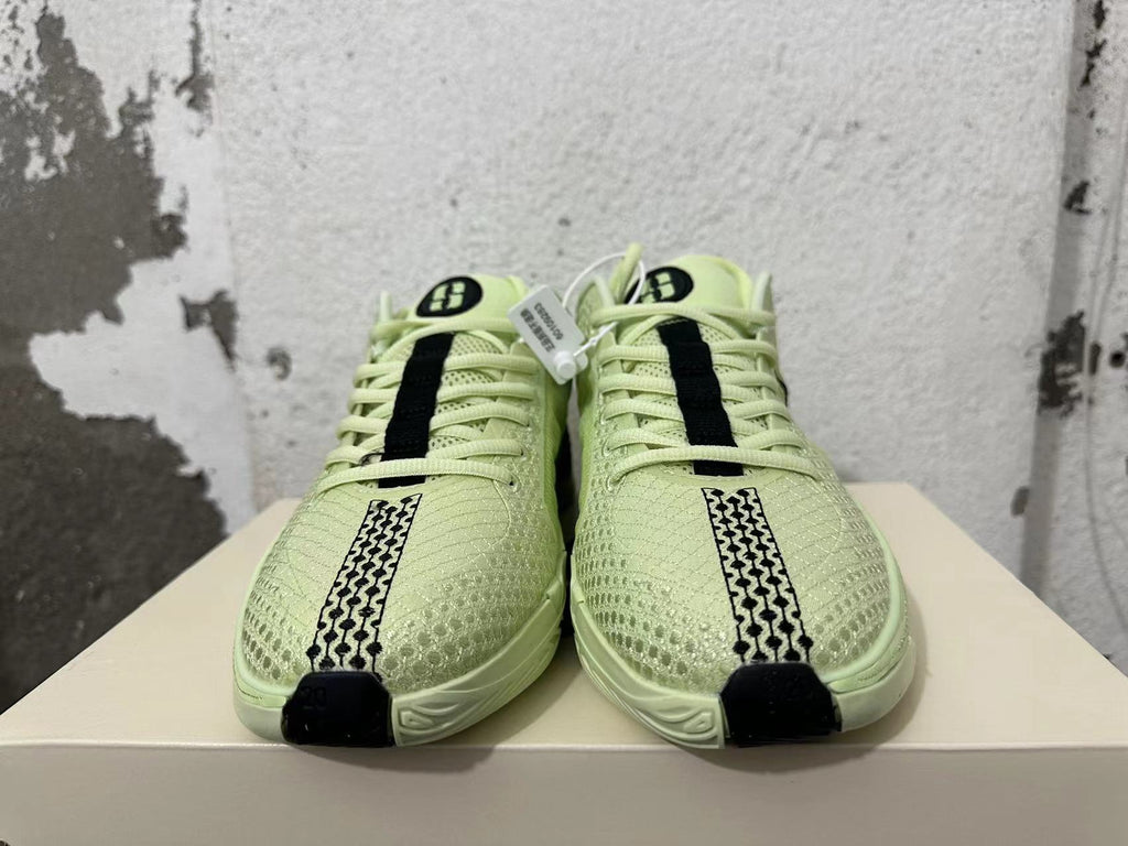Front view showing the patterned forefoot, laces, and black accents on pale yellow-green Nike basketball shoes