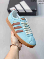 Angled close view of the light blue sneaker with brown stripes, adidas branding, and gum-colored sole.