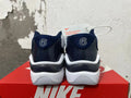 Rear view of white and navy Nike sneakers showing the heels and sole.