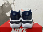 Rear view of white and navy Nike sneakers showing the heels and sole.