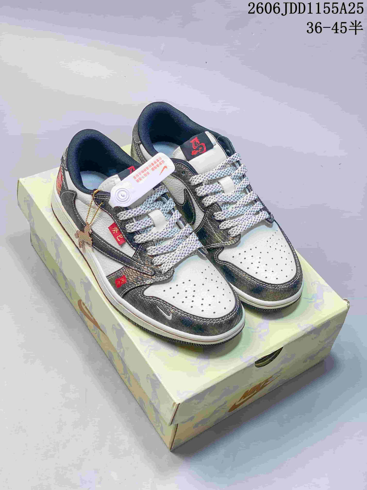 Pair of white and dark Jordan low-top sneakers displayed on a patterned shoebox.