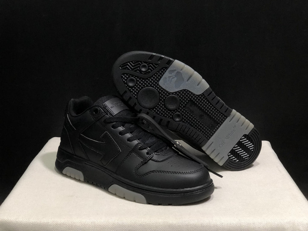 Angled view of the black sneaker pair with one shoe lifted to show the patterned outsole and light outsole sections.