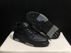 Angled view of the black sneaker pair with one shoe lifted to show the patterned outsole and light outsole sections.