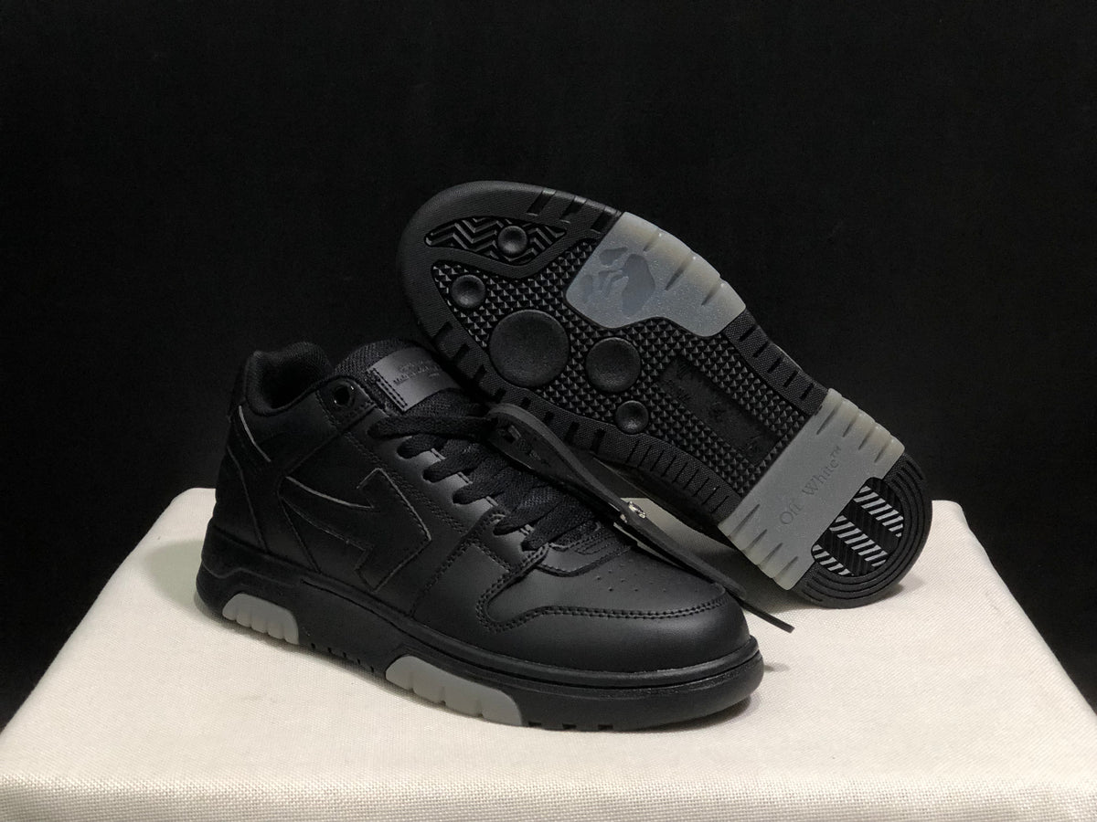 Angled view of the black sneaker pair with one shoe lifted to show the patterned outsole and light outsole sections.
