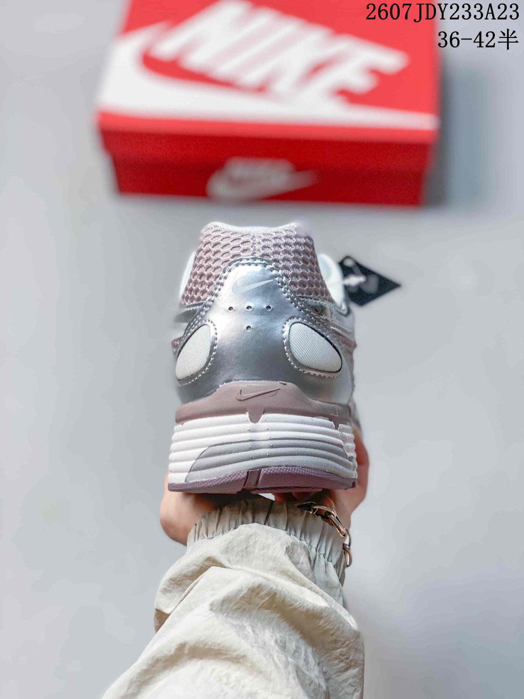Rear view of a silver and white sneaker showing the padded heel, layered upper, and textured outsole; size range 36–42.5 is visible.