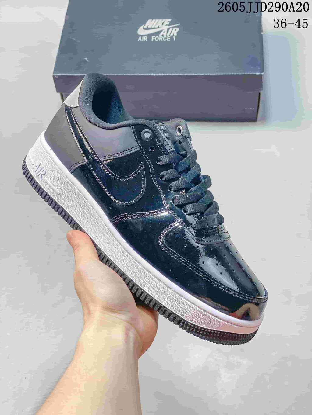 Glossy dark low-top sneaker with a white midsole and layered panels