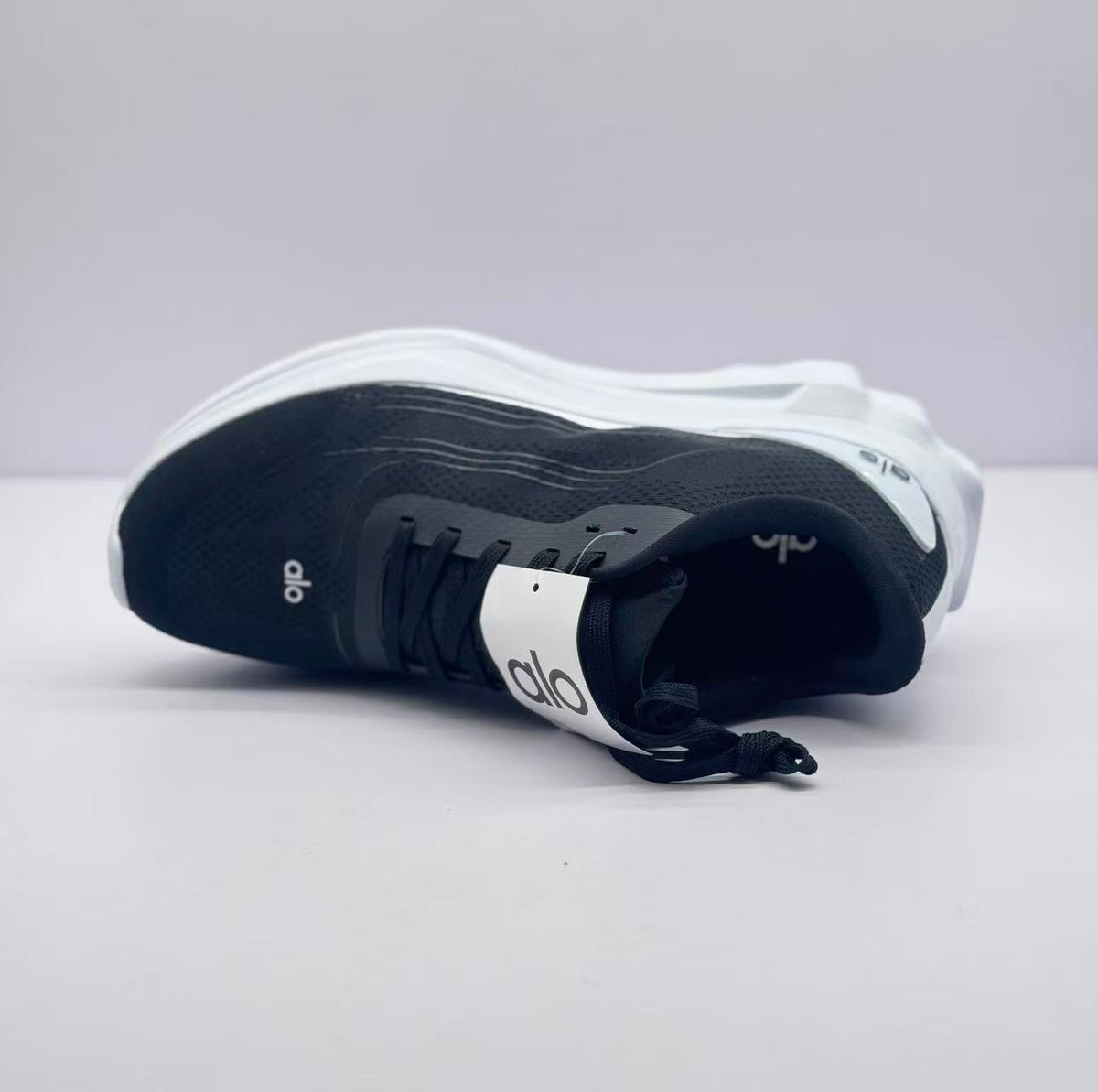Top view of one sneaker displaying the tongue branding, laces, and textured upper.