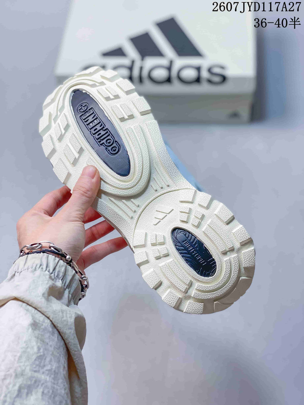 Underside view of the sneaker showing the cream outsole with raised geometric tread and dark adidas branding inserts.