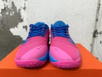 Front view showing pink uppers, blue laces, and pink outsoles