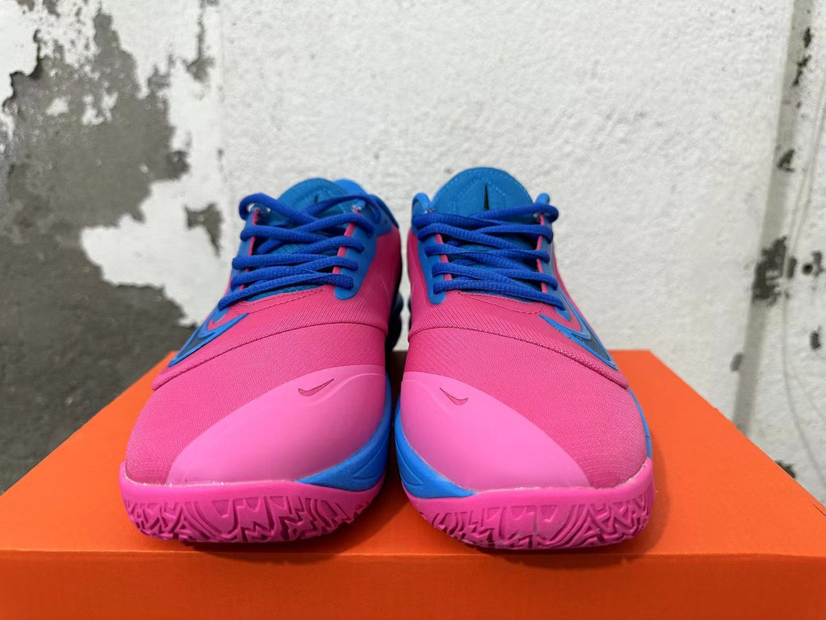 Front view showing pink uppers, blue laces, and pink outsoles