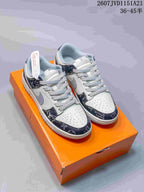 Pair of white, grey, and navy low-top sneakers displayed on an orange shoe box.