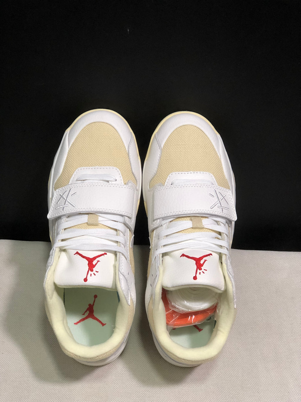 Top-down view showing the cream toe panels, white straps, laces and red tongue logos.