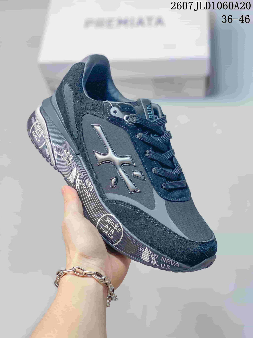 Three-quarter side view of a black and gray Premiata trainer showing the side logo, layered upper, and printed sole details.