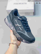 Three-quarter side view of a black and gray Premiata trainer showing the side logo, layered upper, and printed sole details.