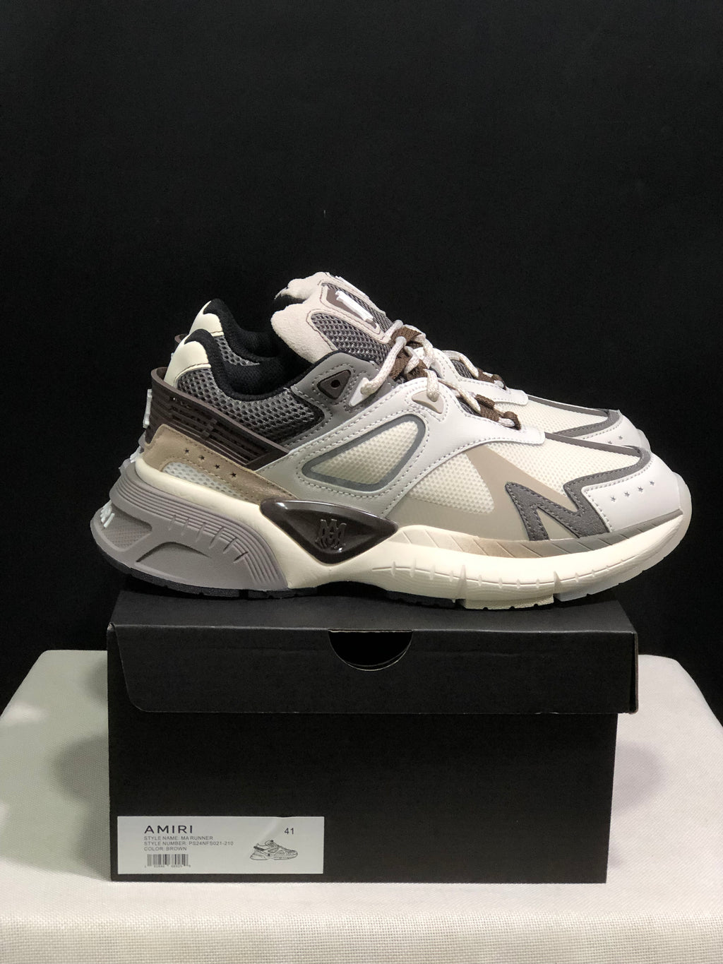 Side view of the sneaker positioned on a black box with a visible size label.
