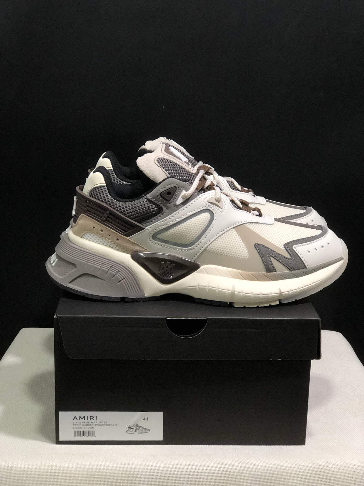 Side view of the sneaker positioned on a black box with a visible size label.