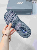 Underside view of a dark gray New Balance sneaker showing the segmented rubber outsole and textured tread.