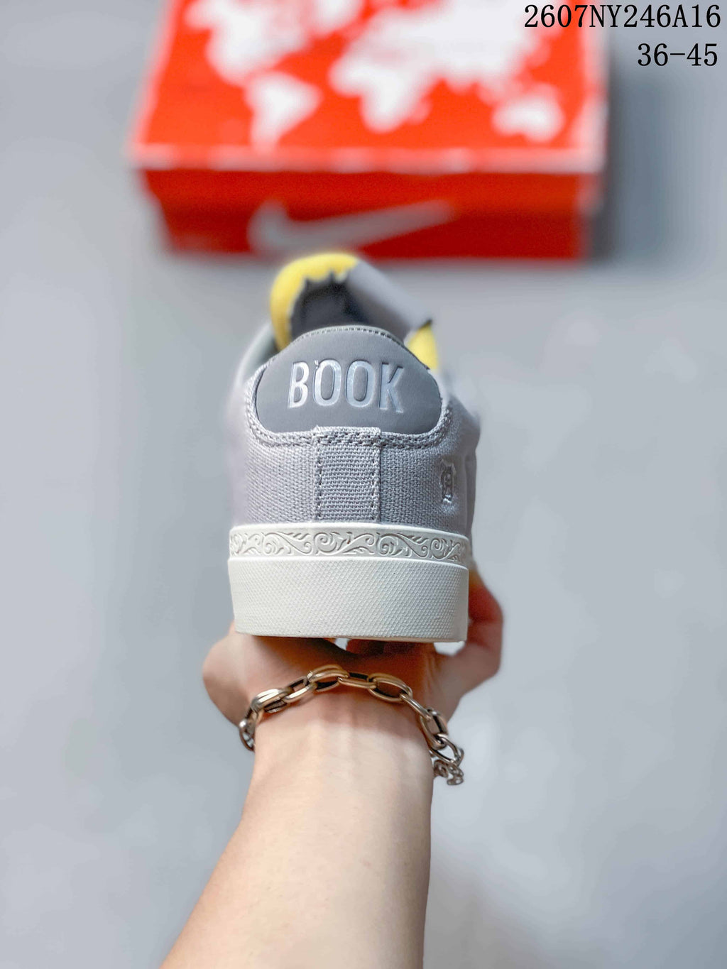 Rear view of the gray sneaker showing “BOOK” lettering on the heel and a decorative patterned midsole strip.