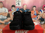 Front view of black high-top basketball shoes with black laces and blue pull tabs.