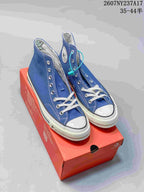 Blue Converse high-top sneakers displayed on a red shoebox, showing the white toe caps, laces, and side patches.