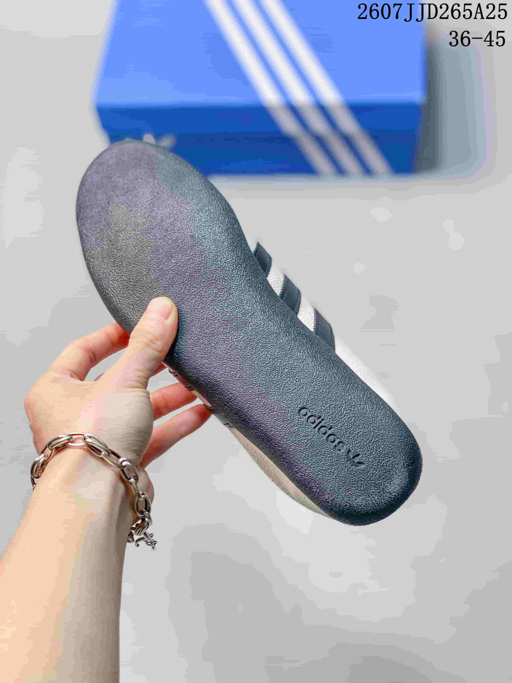 Close-up of the dark textured outsole of a white adidas sneaker, with adidas branding molded near the heel.