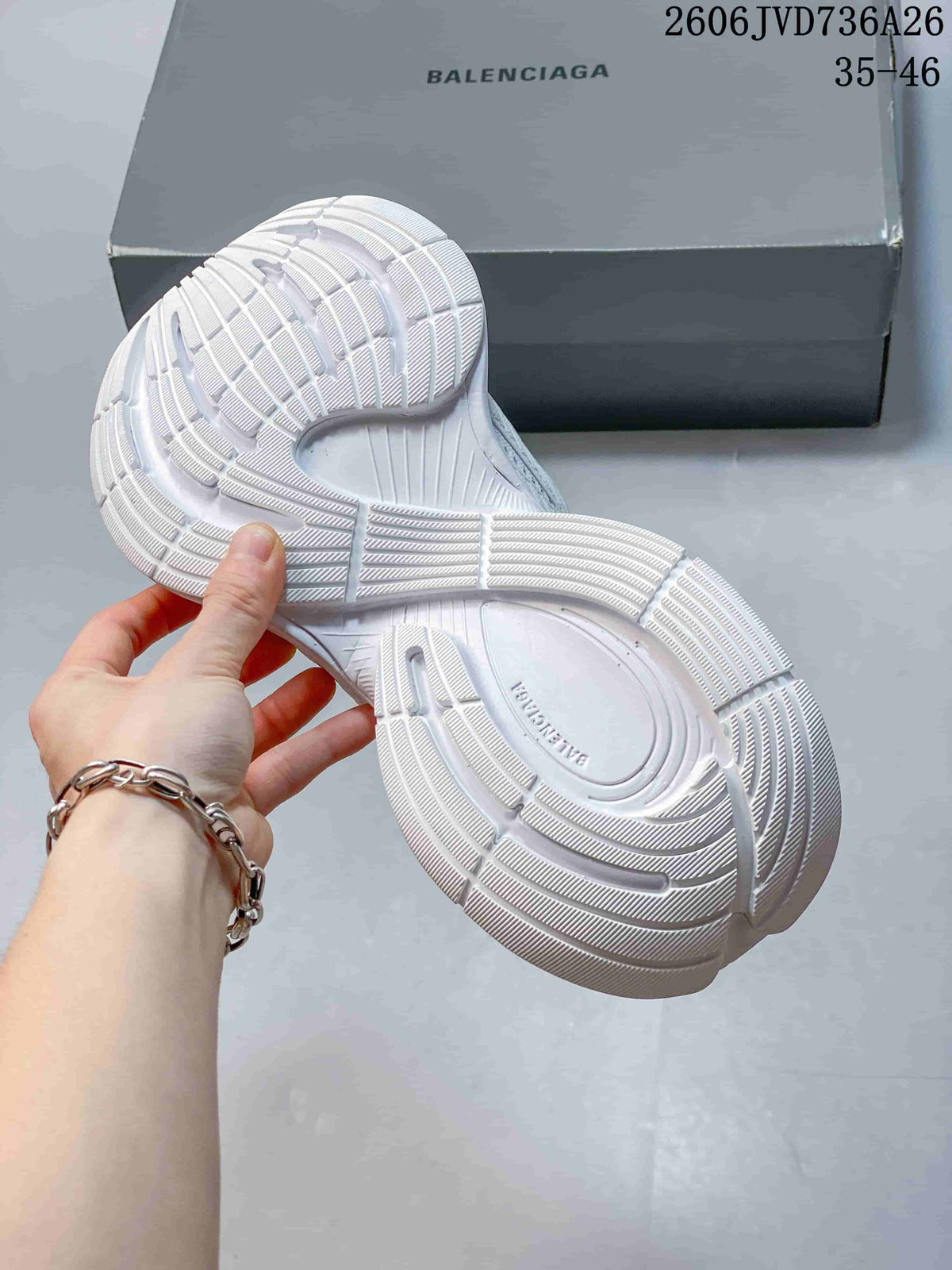 Underside of a white sneaker showing its patterned tread and sculpted sole.