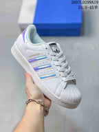 White adidas Superstar sneaker with iridescent blue and purple serrated stripes.