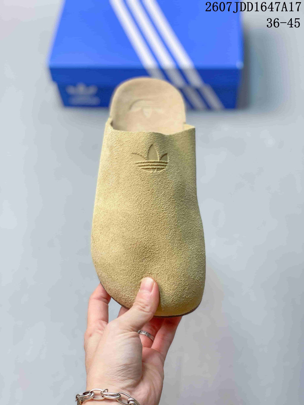 Top view of a beige slip-on mule showing the closed rounded toe and embossed adidas trefoil logo.