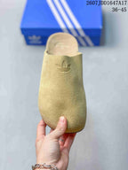 Top view of a beige slip-on mule showing the closed rounded toe and embossed adidas trefoil logo.