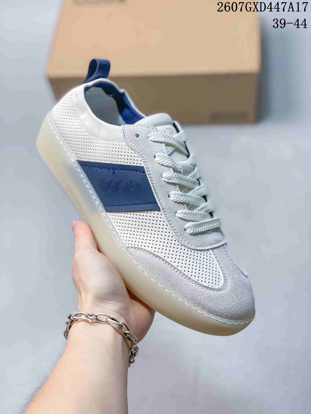 Angled side view of a white ECCO sneaker with blue side branding, perforated panels, laces, and a light-colored outsole.