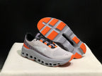 On Cloud X sneakers shown from the side with one shoe outsole facing up, highlighting orange tread sections.
