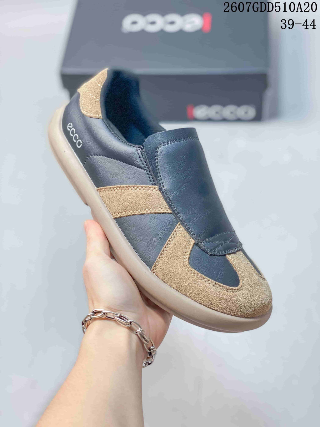 Angled close-up of a navy and tan ECCO sneaker with the ECCO logo visible at the side; image text shows style code 2607GDD510A20 and sizes 39–44.