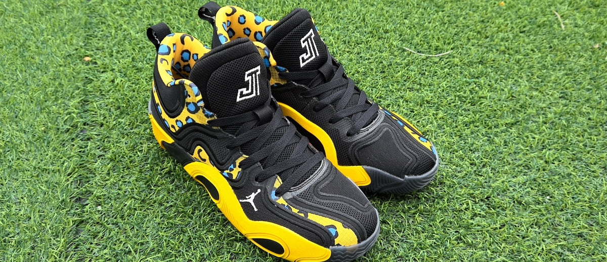 Pair of black and yellow leopard-print high-top sneakers on grass