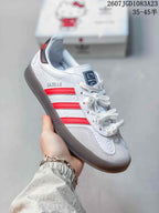 Angled side view showing the white upper, red stripes, Gazelle side branding, Hello Kitty graphics, and dark outsole.