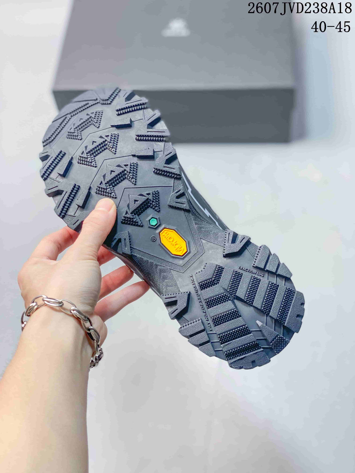 Close view of the hiking shoe outsole showing a large geometric lug pattern and branded outsole inserts.