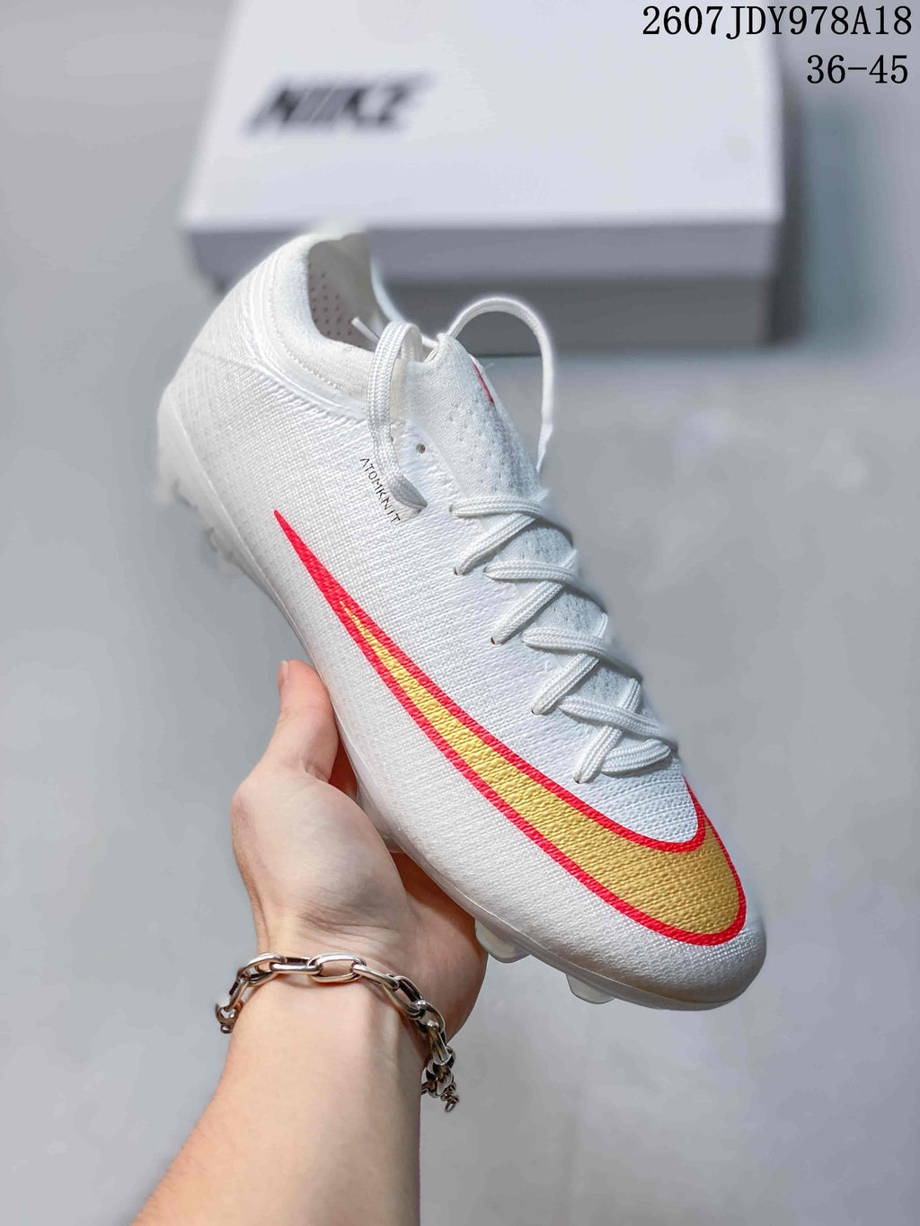 Angled side view of the white Nike soccer cleat showing the textured upper, lace-up closure, and gold-and-red Swoosh.