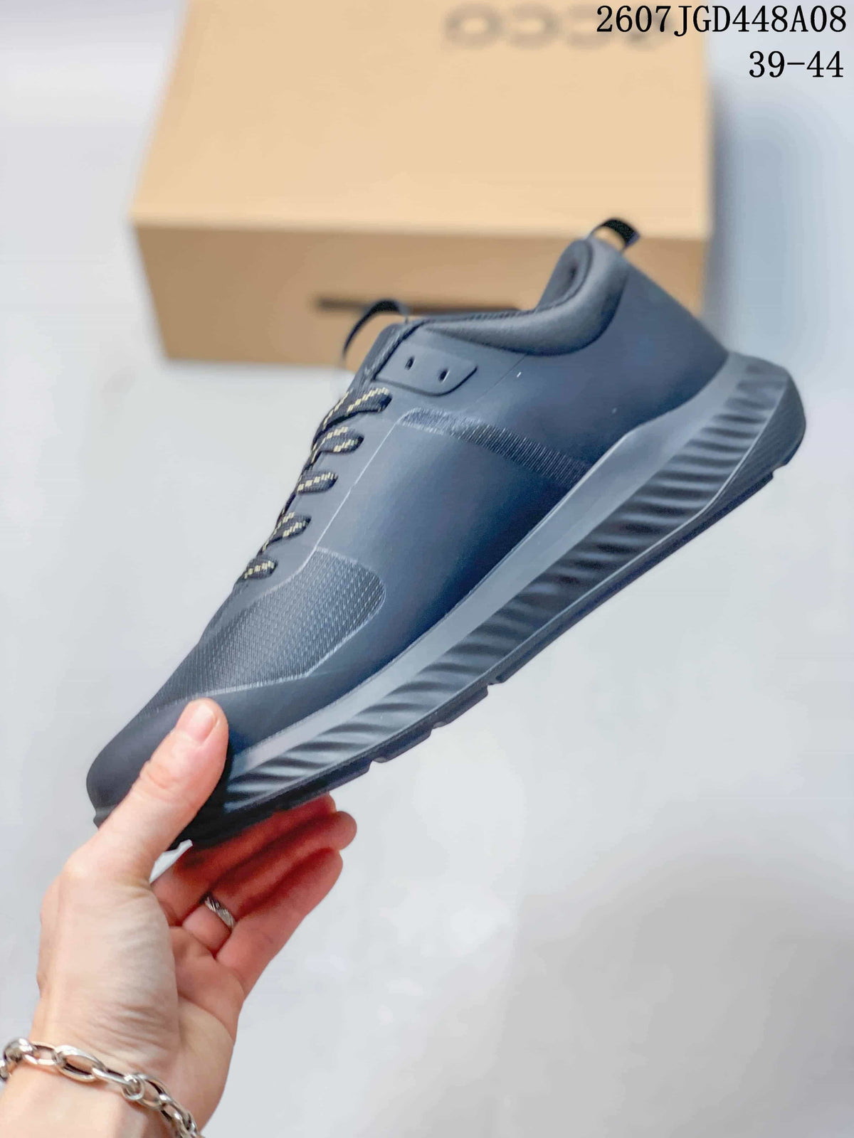 Side view of a dark gray ECCO sneaker showing the layered upper panels, lace-up front, heel pull tab, and textured outsole.