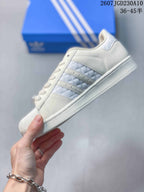 Side view of the white sneaker showing the quilted side panel, three stripes, lace eyelets, and rubber sole.
