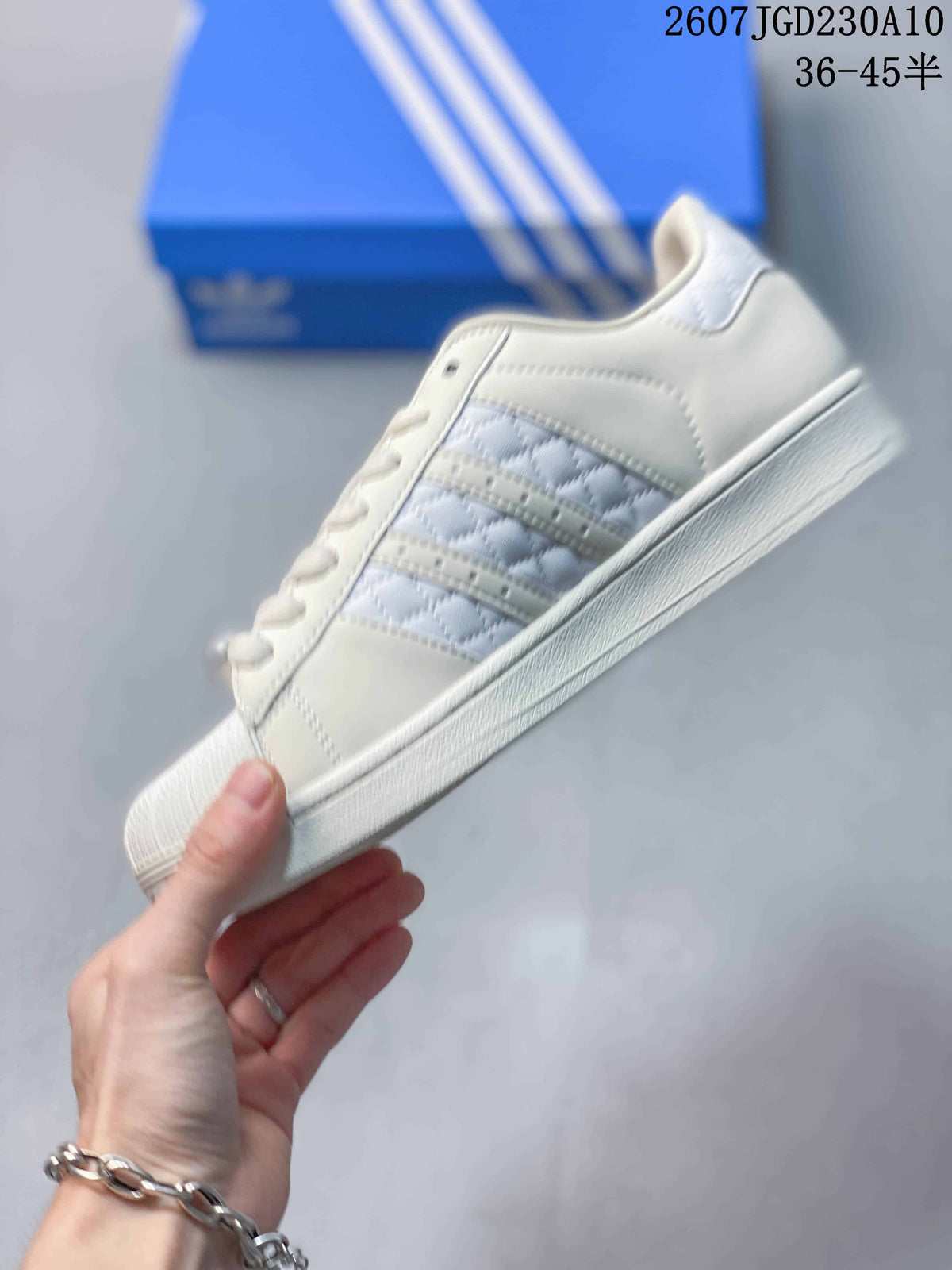 Side view of the white sneaker showing the quilted side panel, three stripes, lace eyelets, and rubber sole.