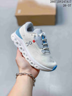 Angled side view of the white and gray running shoe with blue accents and open outsole sections.