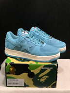 Pair of light blue BAPE STA low-top sneakers displayed on a camouflage-branded shoebox; the box label visibly shows US 8, UK 7, EU 41, and CM 26.
