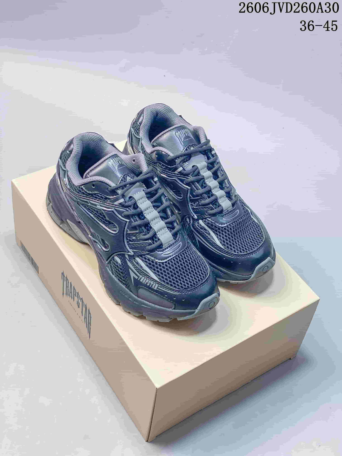Pair of dark gray Trispeed 3000 Trainer sneakers shown on a branded box