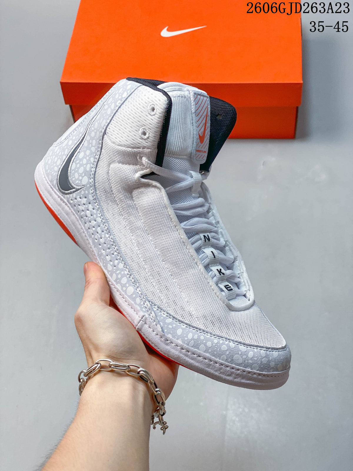 Side view of a white Nike Inflict 4 wrestling shoe with a patterned overlay and dark Swoosh.